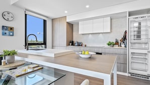 A modern kitchen with a large window, white cabinetry, and a built-in refrigerator. - Stylish 2-bed Apartment With Rooftop BBQ Access (Perth)