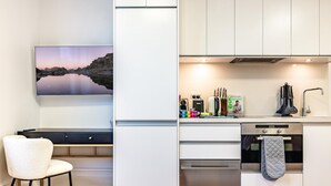 Una cocina moderna con armarios blancos, horno empotrado y cafetera.
