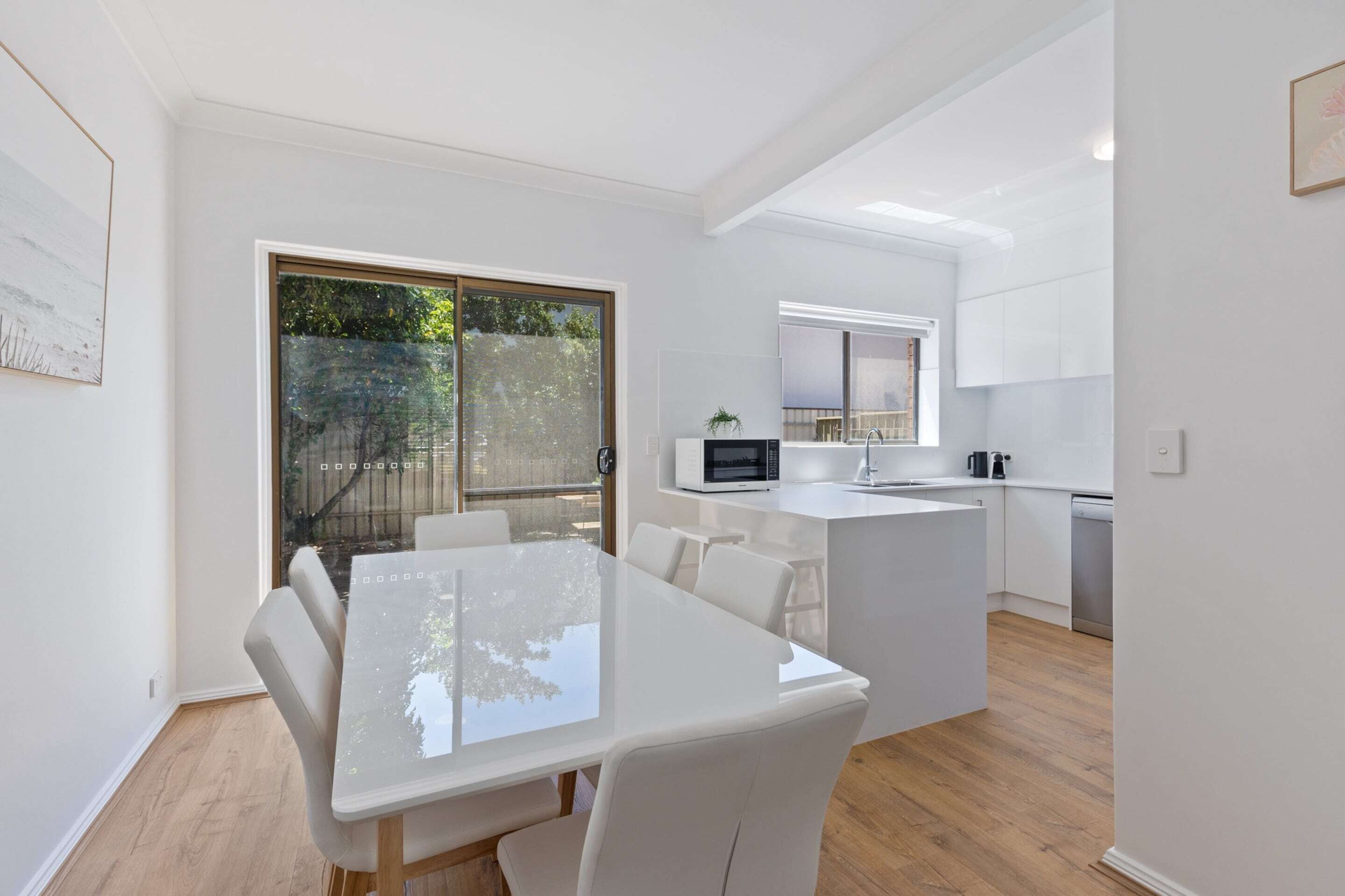 A modern kitchen with white cabinets, a microwave, and a sink.