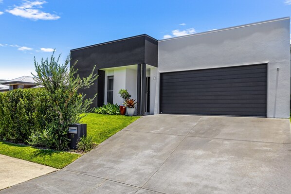 A modern two-story house with a garage, a well-maintained lawn, and a mailbox. - Premium 4-bed Coastal Escape With BBQ and Pool (Sunshine Coast)
