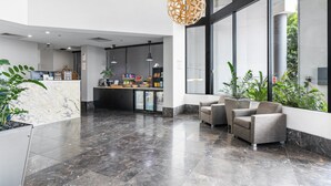 Un vestíbulo amplio con mostrador de recepción, zona de estar y grandes ventanales con vistas al exterior.