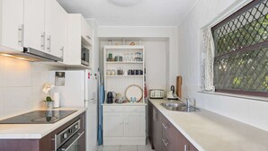 A compact kitchen with white cabinets, a built-in oven, a microwave, and a small countertop with a sink. - Great Location 1-bed With Pool (Sunshine Coast)