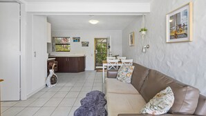 A living room with a brown leather sofa, a patterned throw blanket, and a white vase with a polka dot pattern. - Great Location 1-bed With Pool (Sunshine Coast)