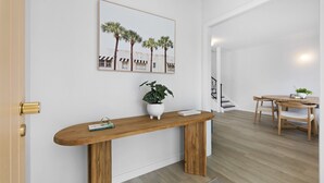 Ein modernes Interieur mit einem Holzkonsolentisch, einer Topfpflanze und einem gerahmten Kunstwerk an der Wand.