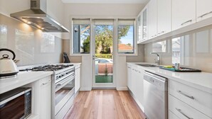 A modern kitchen with white cabinetry, a gas stove, an oven, and a dishwasher. - Chic 2-bed Home By Bustling Shops (Melbourne)