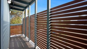 A covered outdoor area with a wooden slatted fence, metal beams, and a tiled floor. - Chic 2-bed Home By Bustling Shops (Melbourne)