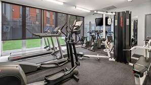 A gym with treadmills, elliptical machines, and weightlifting equipment. - Sleek Kensington 2-bed With BBQ Area & Gym (Melbourne)