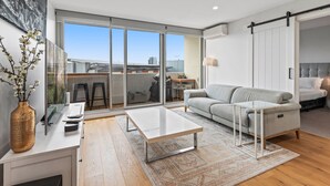 A modern living room with a sofa, coffee table, and a sliding glass door leading to a balcony. - Sleek Kensington 2-bed With BBQ Area & Gym (Melbourne)