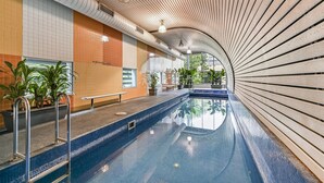 Ein Innenpool mit gewölbter Decke, gefliesten Wänden und Kübelpflanzen entlang der Seiten.