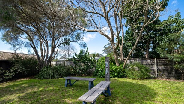 Un jardin avec deux tables de pique-nique en bois et une clôture en bois.