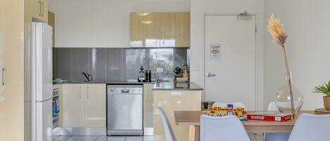 Een moderne keuken met een vaatwasser, een koelkast en een eethoek met een tafel en stoelen.