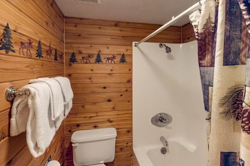 Un baño con paneles de madera, un inodoro, una ducha con cortina y un perchero para toallas.