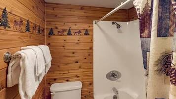 Un baño con paneles de madera, un inodoro, una ducha con cortina y un perchero para toallas.