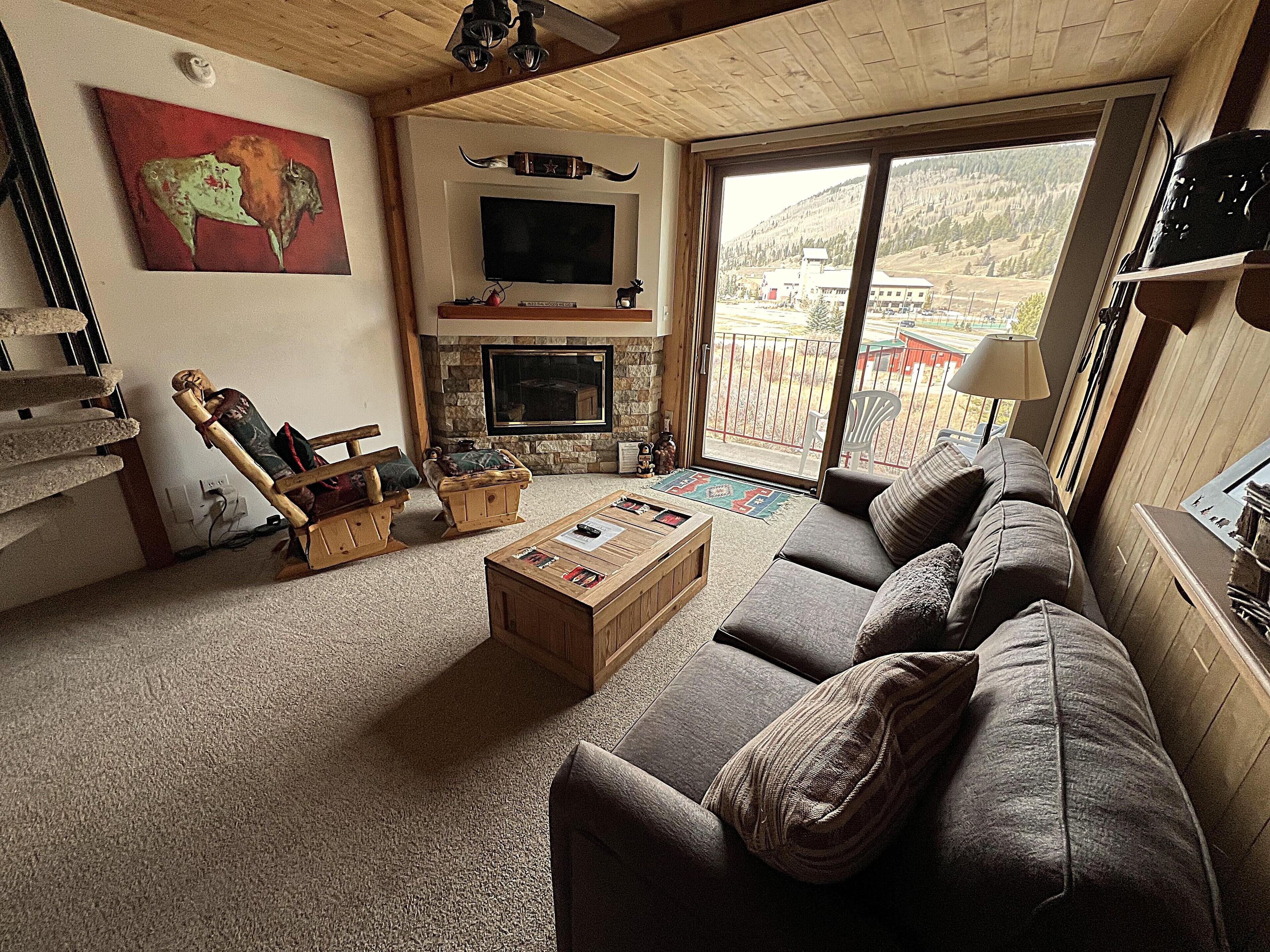 Ein gemütliches Wohnzimmer mit Kamin, großem Fenster und Blick ins Freie.