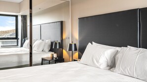 A modern hotel room with a large bed, a nightstand with a lamp, and a large mirror reflecting the room. - Spacious Apartment in Heart of Southbank (Melbourne)