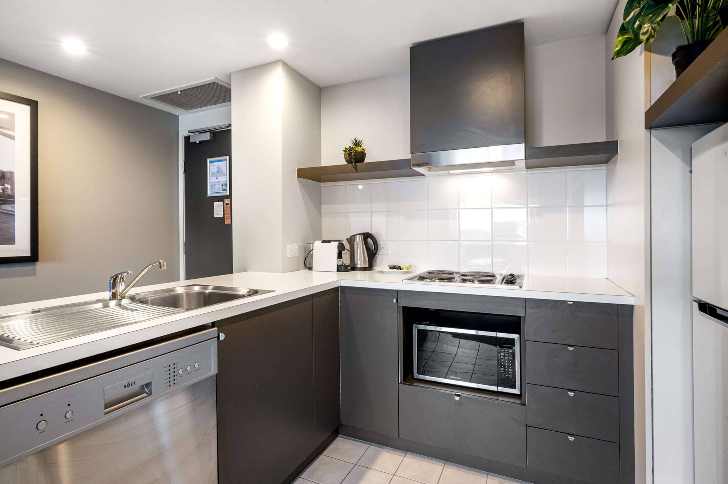A modern kitchen with a dishwasher, oven, and stainless steel sink.