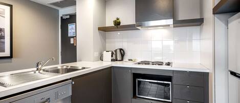 A modern kitchen with a dishwasher, oven, and stainless steel sink.