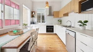 Una cocina moderna con armarios blancos, una mesa de comedor de madera y un lavavajillas empotrado.