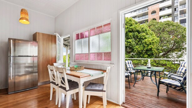 Una cocina moderna con un refrigerador de acero inoxidable, armarios de madera y una zona de comedor con una mesa y sillas.