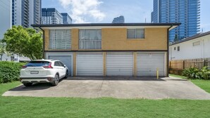 Een modern, tweelaags gebouw met een garage, een witte auto ervoor en een verzorgd gazon.