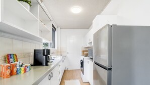 Een moderne keuken met witte kastjes, een roestvrijstalen koelkast en een koffiezetapparaat op het aanrecht.