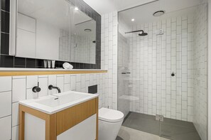 Une salle de bain moderne avec un lavabo blanc, des toilettes et une douche à parois de verre.