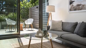 Una sala de estar moderna con una mesa de vidrio, sillas blancas, un sofá gris y una lámpara de pie.