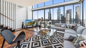 Una sala de estar moderna con vista a la ciudad, un sofá, una mesa de centro y un televisor.