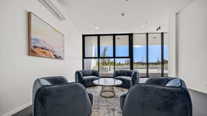 A modern meeting room with a large window, black upholstered chairs, a round table, and a painting on the wall. - Chic 1-bed With Sophisticated Decor, (Canberra)
