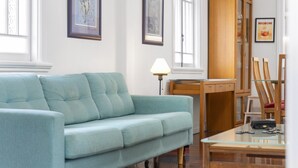 A living room with a light blue sofa, a wooden dining table, and a lamp.