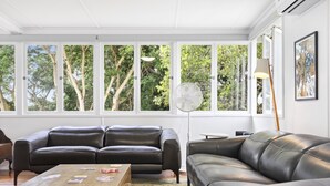 A modern living room with a black leather sofa, a wooden coffee table, and a floor lamp.