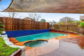 A swimming pool with a wooden deck and a blue tiled border. - Modern 3-bed With Pool & Water Views by Beach (Sydney)
