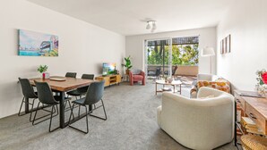 Ein modernes Wohnzimmer mit Essbereich, großen Fenstern und einem Gemälde an der Wand.