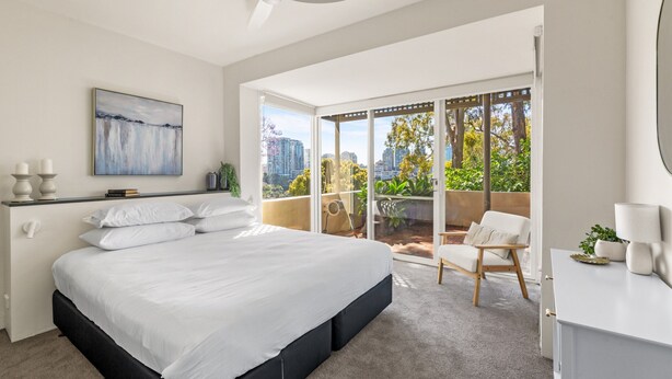 Ein modernes Schlafzimmer mit großem Bett, einem Balkon mit Stadtblick und einem minimalistischen Design.