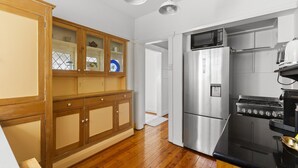 Eine Küche mit Holzausstattung, einem Edelstahlkühlschrank, einem Herd und einer Mikrowelle.