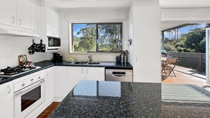 Une cuisine moderne avec des meubles blancs, un plan de travail en granit et une fenêtre donnant sur un jardin.