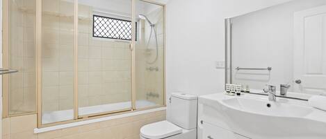 Une salle de bain moderne avec une douche à parois de verre, des toilettes blanches et un meuble-lavabo avec un évier et un miroir.