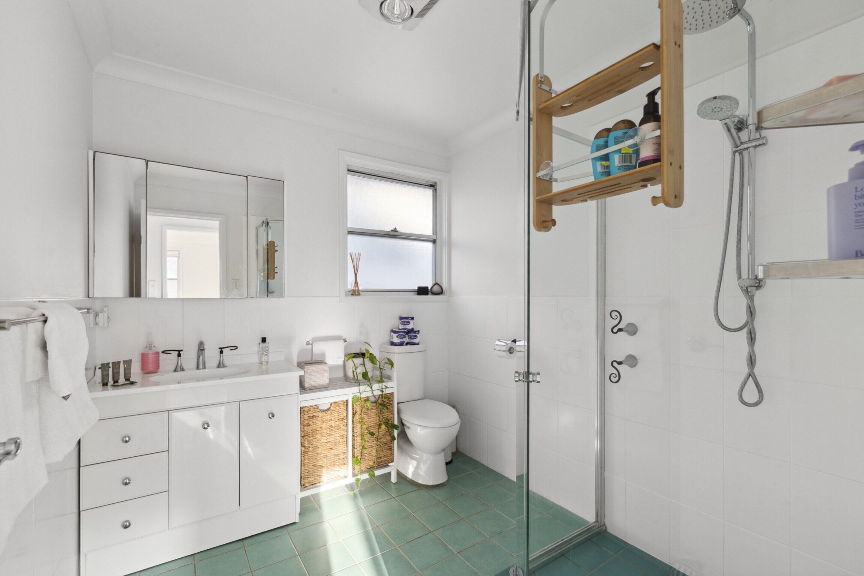Un baño moderno con tocador blanco, cabina de ducha de vidrio y ventana que proporciona luz natural.