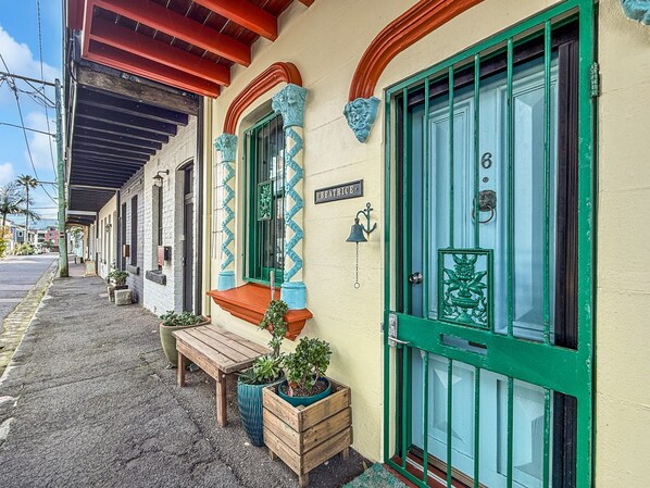 A building with a green door, a bench, and potted plants outside. - Charming Townhouse Steps From Newcastle Beach (Newcastle)