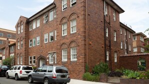 A multi-story brick building with a symmetrical facade, large windows, and a central entrance. - Spacious 2-bed Apartment in the Heart of Manly (Sydney)