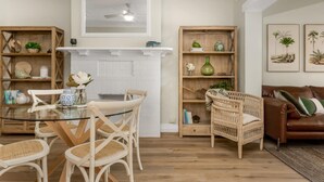 A living room with a glass-top dining table, wicker chairs, a brown leather sofa, and a fireplace. - Spacious 2-bed Apartment in the Heart of Manly (Sydney)
