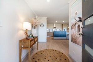 A modern kitchen with blue cabinets, a wooden dining table with a lamp, and a round rug. - Large Upstairs Family Stay Near Middleton Beaches (Middleton)