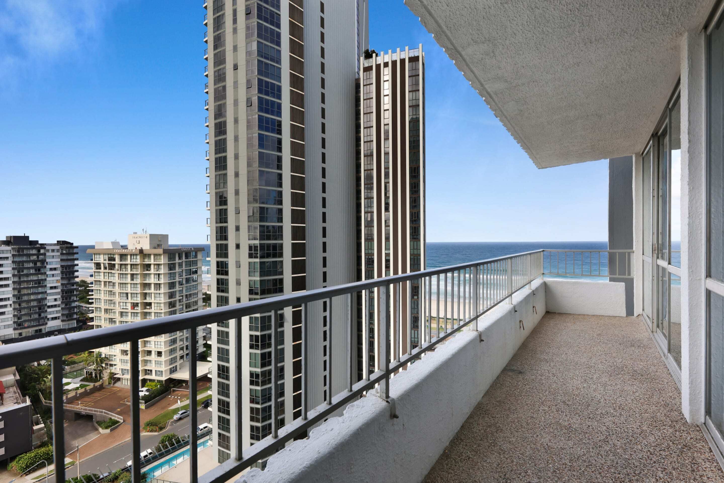 A balcony with a view of tall buildings and the ocean.