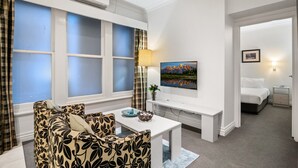 A hotel room with a sofa, a small table, a TV, and a bed. - Melbourne CBD 1-bed With A/C Close to Theatres (Melbourne)