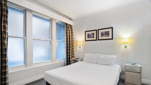 A hotel room with a large bed, two bedside tables, a nightstand, and a window with curtains. - Melbourne CBD 1-bed With A/C Close to Theatres (Melbourne)