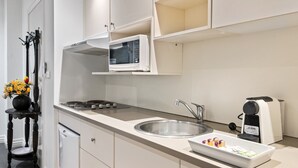 A modern kitchen with white cabinetry, a built-in microwave, a sink, and a coffee machine. - Melbourne CBD 1-bed With A/C Close to Theatres (Melbourne)