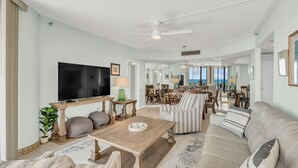 A spacious living room with a flat-screen TV, comfortable seating, and a view of the ocean. - 9th Floor! Awesome Views! Free Beach SRVC! Free Beach Bonfires M & Fri Nights (Miramar Beach)