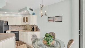 A modern kitchen with white cabinets, a black refrigerator, and a coffee maker on the counter. - 9th Floor! Awesome Views! Free Beach SRVC! Free Beach Bonfires M & Fri Nights (Miramar Beach)
