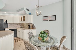 A modern kitchen with white cabinets, a black refrigerator, and a coffee maker on the counter. - 9th Floor! Awesome Views! Free Beach SRVC! Free Beach Bonfires M & Fri Nights (Miramar Beach)