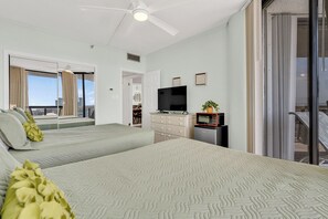A hotel room with two beds, a television, a minibar, and a view of the city.